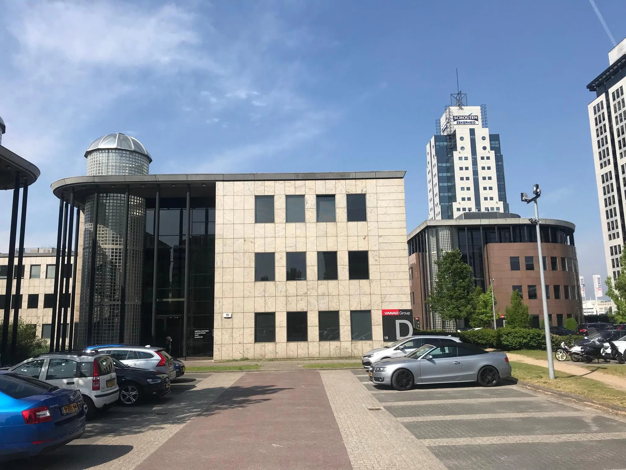 Kantoorgebouw aan het Rivium Quadrant met parkeervakken en diverse geparkeerde auto's op de voorgrond.